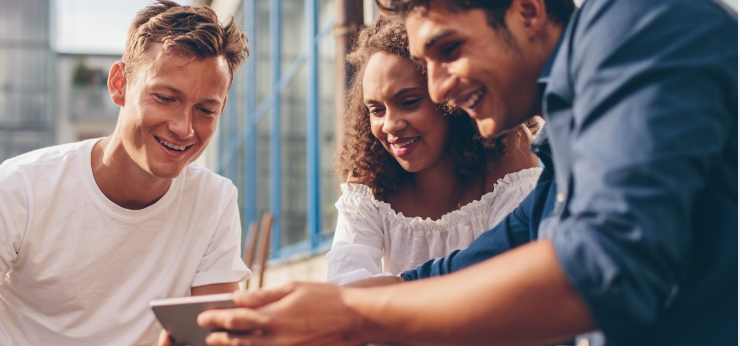 Three Spectrum Mobile customers looking at a mobile phone.